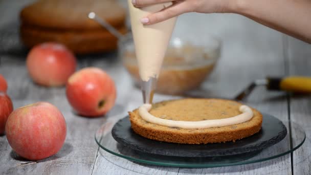 Unerkennbare Konditorin quetscht Sahne auf appetitlichen Schichtkuchen in Küche. — Stockvideo