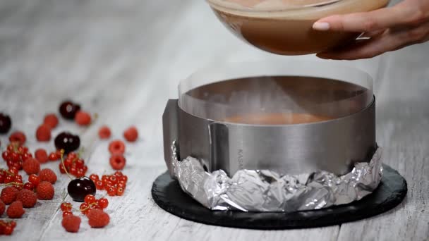 Fazendo bolo de mousse de chocolate três caseiro. Derramando a mousse de chocolate na forma . — Vídeo de Stock