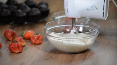 Ev yapımı kekler için bir karıştırıcı ile çilekli tereyağı krema yapma