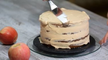 Tanınmayan kadın pasta yemek mutfakta iştah açıcı katman kek üzerine krema sıkma.