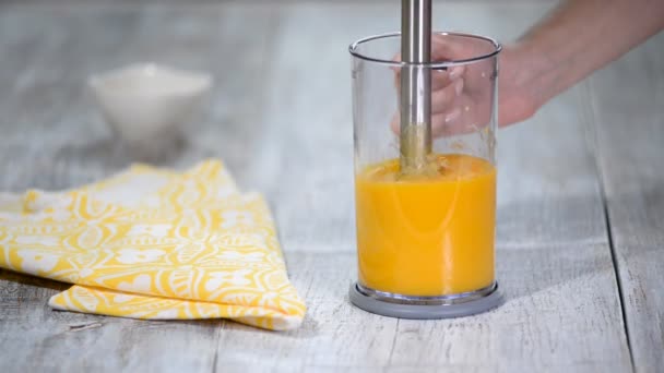 Vrouw maalt perziken met een blender. Perzik puree maken. — Stockvideo