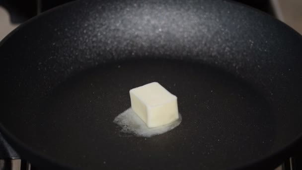Stukje boter dat smelt op non-stick koekenpan. — Stockvideo
