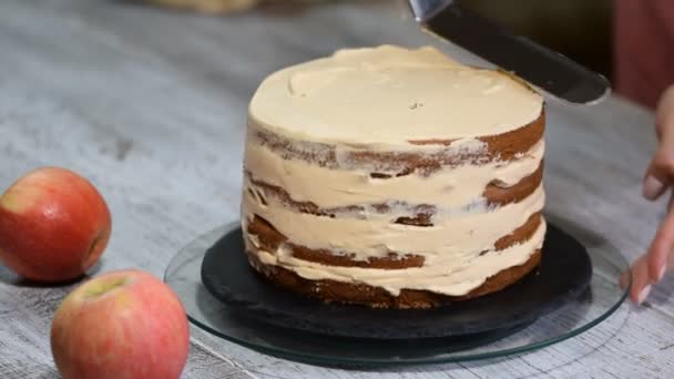 Pastelaria feminina irreconhecível cozinhar espremendo creme no bolo camada apetitosa na cozinha . — Vídeo de Stock
