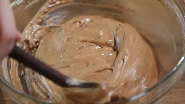 Konditorpigen omrører dejen med den kulinariske spatel til bagning af chokoladekikskage. konfektureprodukter til hjemmebrug . – Stock-video