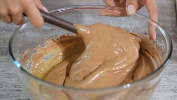 Ein Konditor kocht einen Teig. eine Hand mit einem Plastikspachtel rührt den Teig in einer Glasschüssel zum Backen eines Schokoladenkekses. — Stockvideo