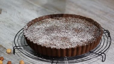 Masanın üzerinde bir plaka üzerinde fındık ile çikolatalı tart.