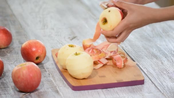 Handen een koken appel peeling op een houten bord. — Stockvideo