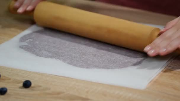 Uitrollen van deeg tussen twee lagen van het bakken van perkament. — Stockvideo