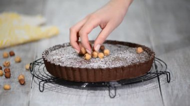 Masanın üzerinde bir plaka üzerinde fındık ile çikolatalı tart.