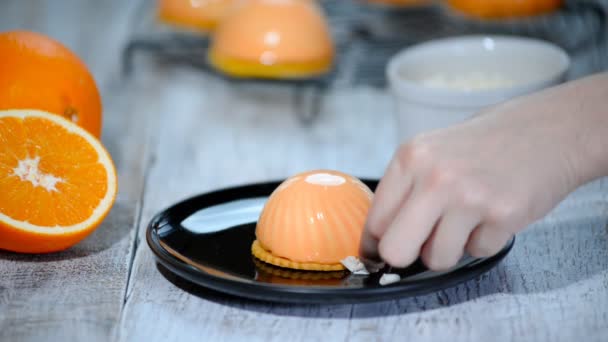 Prozess der Herstellung von köstlichem Dessert. Unerkennbare Konditorenhände dekorieren orange glasierte Kuchen. — Stockvideo