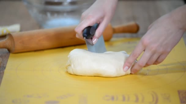 Bäckerin schneidet rohe Teigrolle mit Mehl auf dem Tisch in Stücke. — Stockvideo
