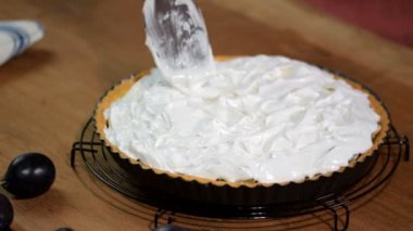 The process of cooking a pie with plums and meringue.