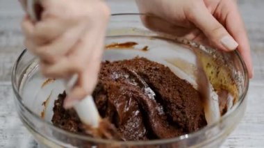 Kız çikolatalı hamur spatula ile hareket ediyor. Çikolatalı hamur yapma süreci.