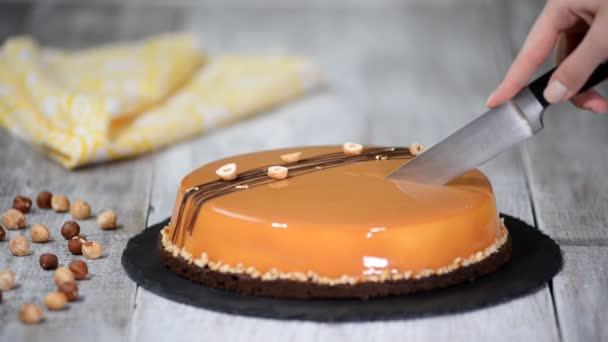 Femme coupant à la main le gâteau de mousse au caramel. Gâteau au caramel, dessert mousse dans une assiette. Gâteau à la mousse avec glaçure miroir — Video