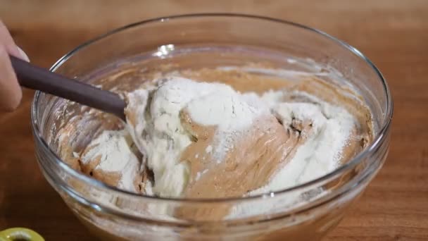 Top view of a female hand with a spatula stirring the chocolate dough in a glass bowl. — Stock Video