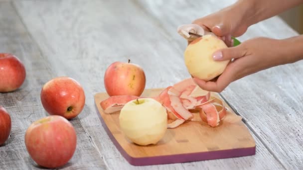 Крупним планом акуратні жіночі руки тримають і очищають червоне яблуко . — стокове відео