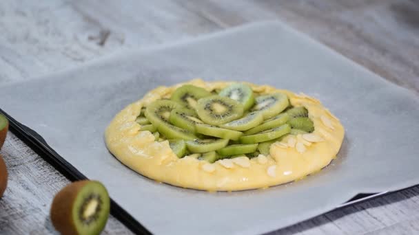 Female hands making galette with fresh kiwi. Sprinkle with almond petals. — Stock Video