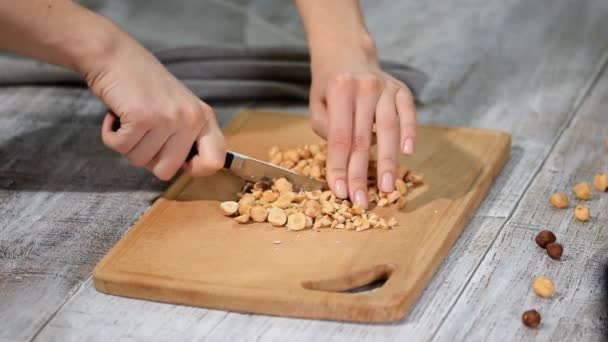 Kvinnliga kockar händerna hugga hasselnötter på trä skärbräda. — Stockvideo