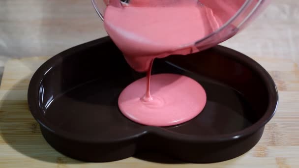 Pouring pink mousse into heart shaped molds. Confectioner making mousse cake in the kitchen — Stock Video