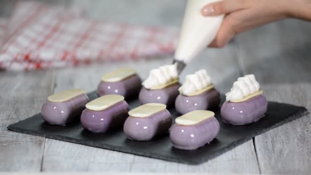 Cukrář zdobí malé dorty se šlehačkou v kuchyni. — Stock video
