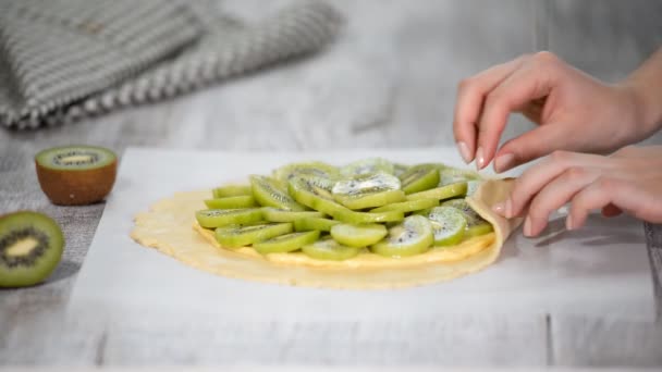 Female hands making galette with fresh kiwi. — Stock Video