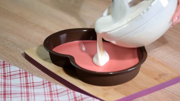Выливание ванильного мусса в формы сердечек. Кондитер делает торт из мусса на кухне . — стоковое видео