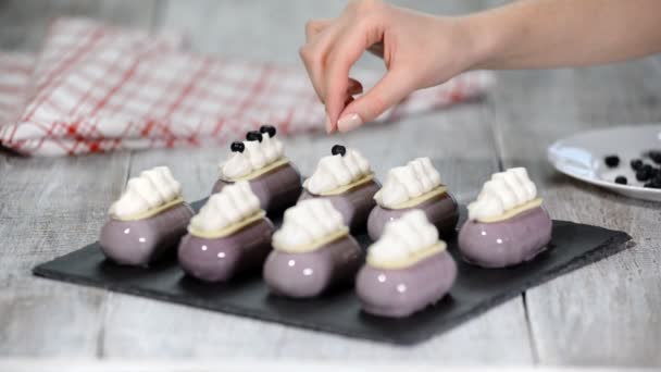 Il pasticcere decora la torta di mousse con un mirtillo Produzione di dessert glassati . — Video Stock