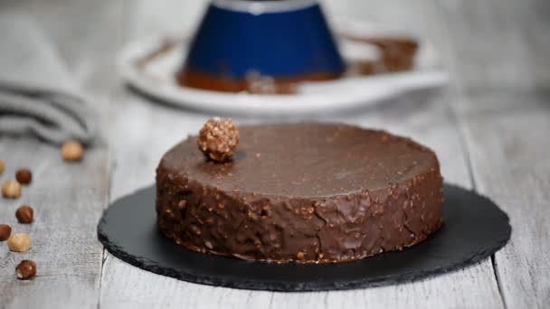 Vrouwelijke handen versieren de chocolate cake met ronde snoep. — Stockvideo