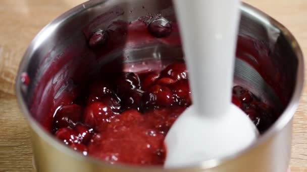 Frau zerkleinert Kirschen mit dem Stabmixer. Zubereitung von Marmelade aus der Kirsche — Stockvideo