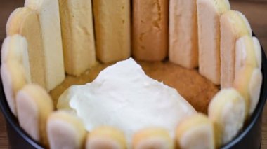 El beyaz krema bir yuvarlak kek üzerine koyarak. Çilek ile Fransız Charlotte pasta yapma.