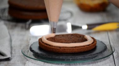 Yakın çekim: bisküvi kremalı kek üzerine bir spiral şeklinde. Çikolatalı krema ile sünger kek. Bir şekerci dükkânı pastada hazırlanması. Tatil için gıda.