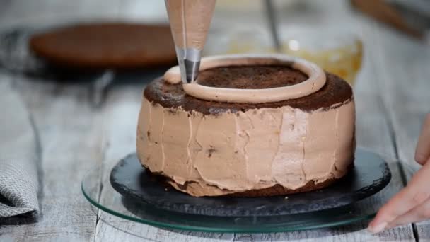 Primer plano: crema de galletas en forma de espiral en el pastel. Pastel de esponja de chocolate con crema. Preparación de la torta en una tienda de dulces. La comida para las vacaciones . — Vídeos de Stock