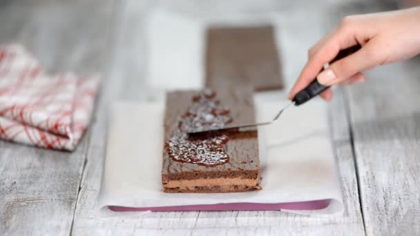 Cocinar haciendo pastel de chocolate capa con mermelada de frambuesa . — Vídeo de stock