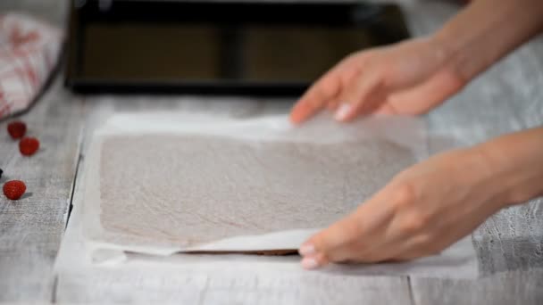Manos femeninas pelando el papel de pergamino de la parte inferior de la torta de esponja . — Vídeo de stock
