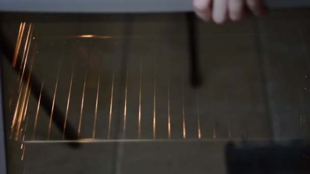 Женская рука кладет поднос для выпечки с тестом из кексов ручной работы в домашнюю духовку . — стоковое видео