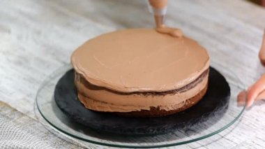 Yakın çekim: bisküvi kremalı kek üzerine bir spiral şeklinde. Çikolatalı krema ile sünger kek. Bir şekerci dükkânı pastada hazırlanması. Tatil için gıda.