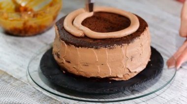 Yakın çekim: bisküvi kremalı kek üzerine bir spiral şeklinde. Çikolatalı krema ile sünger kek. Bir şekerci dükkânı pastada hazırlanması. Tatil için gıda.