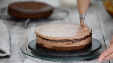 Yakın çekim: bisküvi kremalı kek üzerine bir spiral şeklinde. Çikolatalı krema ile sünger kek. Bir şekerci dükkânı pastada hazırlanması. Tatil için gıda.