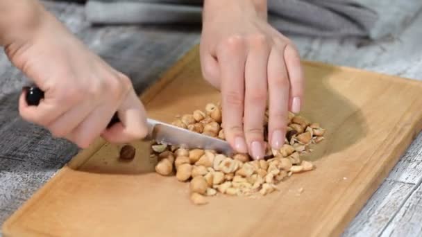 Vrouwelijke chef-koks handen hazelnoten hakken op houten snijplank. — Stockvideo