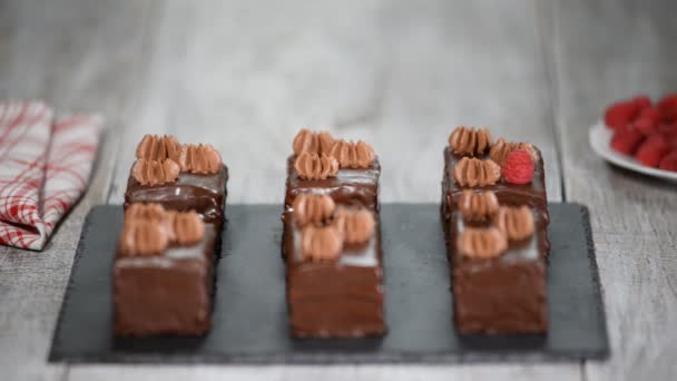 Manos femeninas decorando pasteles de chocolate con frambuesa fresca . — Vídeo de stock