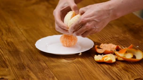 Manos pelando cítricos. Comida saludable. Las manos femeninas pelan mandarina. Sabrosa fruta de mandarina rebanada. Cítricos estacionales . — Vídeos de Stock