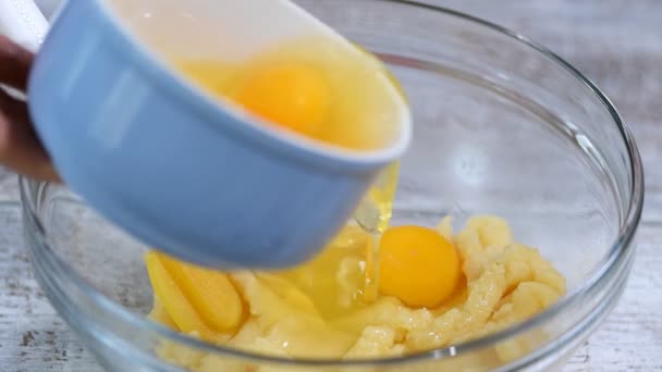 Mezclar ingredientes para hacer pastelería choux en casa. Añadir huevos a la masa — Vídeo de stock