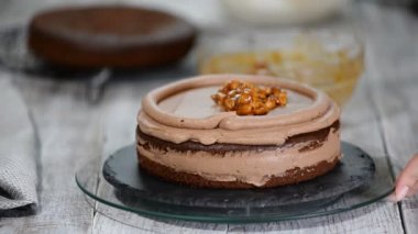 Karamel fıstık kek üzerine doldurma el koyar. Pasta krema ve fındık ile.