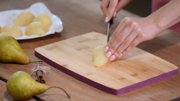 Жінка розрізає грушу на дерев'яній дошці . — стокове відео