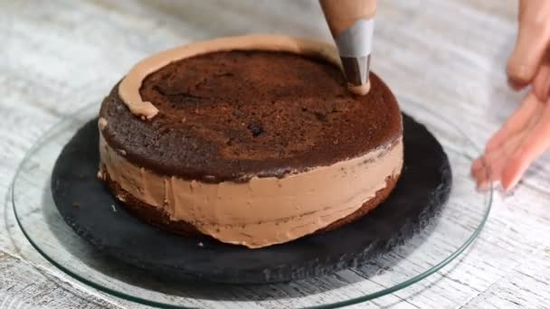 特写: 饼干奶油在蛋糕上的螺旋形式。巧克力海绵蛋糕加奶油。在糖果店准备蛋糕。假期的食物. — 图库视频影像