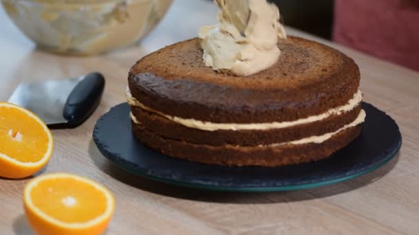 Konditorn sätter grädde på toppen av kakan. Baker smoothing tårta med vispad grädde glasyr. — Stockvideo