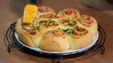 Maya parmesan peyniri ile buns alır. Bir erime tereyağı ve dereotu ile fırça buns.
