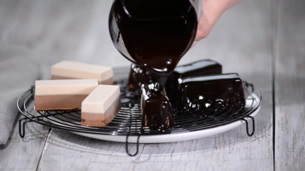 Die Schokoladenspiegelglasur auf ein köstliches Mousse-Dessert gießen. flüssige leckere süße Dessertküche. — Stockvideo