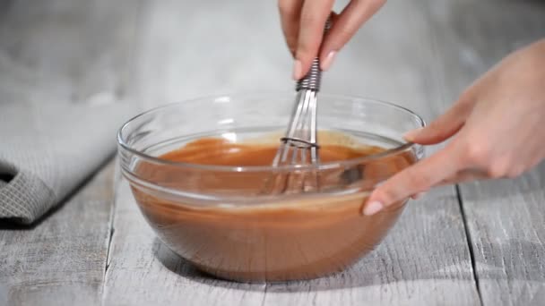 Frau mixt Schokoladencreme mit Schneebesen für Schokoladenkuchen. — Stockvideo