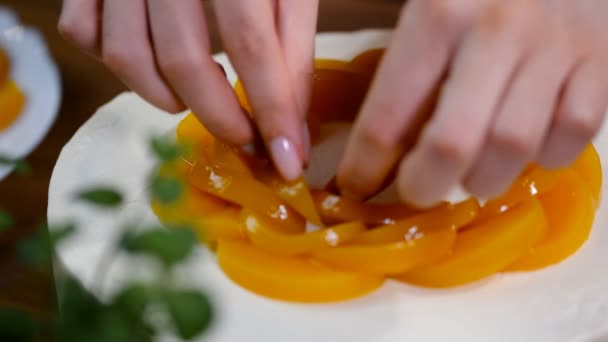 Las manos femeninas decoran el pastel con melocotones . — Vídeo de stock